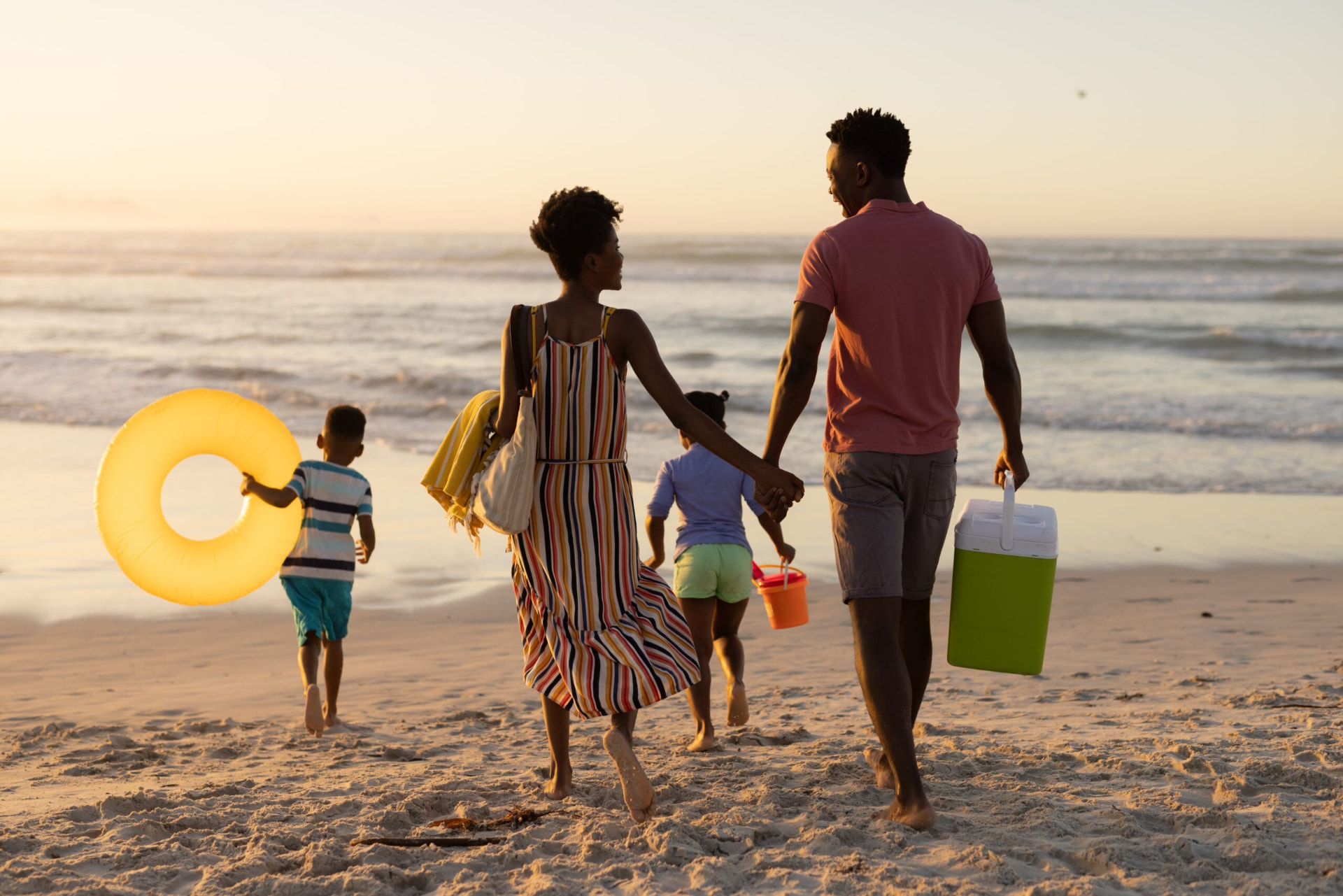 Família caminhando na praia ao pôr do sol